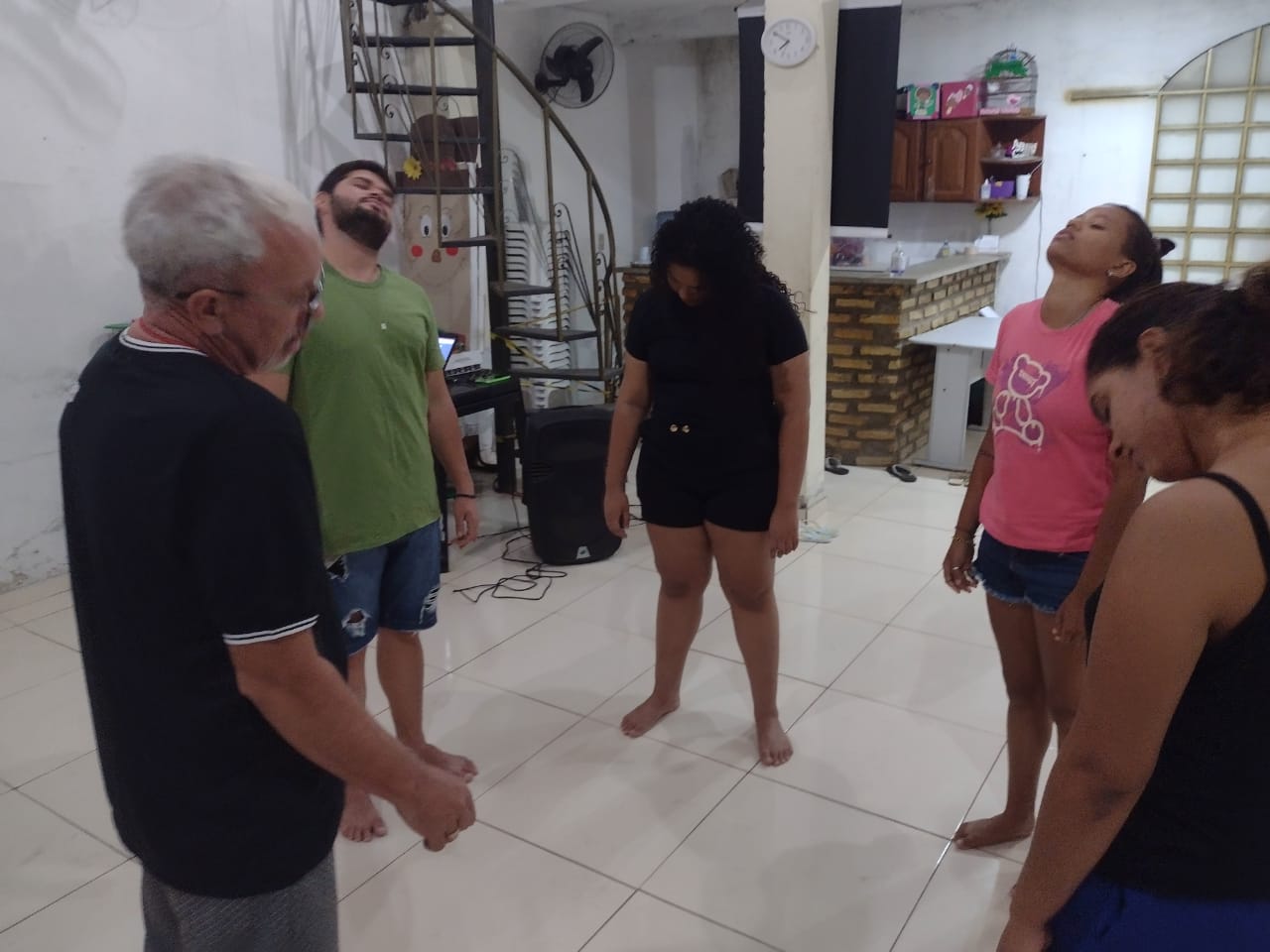 Grupo em exercício de teatro no salão da Fundação, descalço, em círculo, com escada de ferro ao fundo.